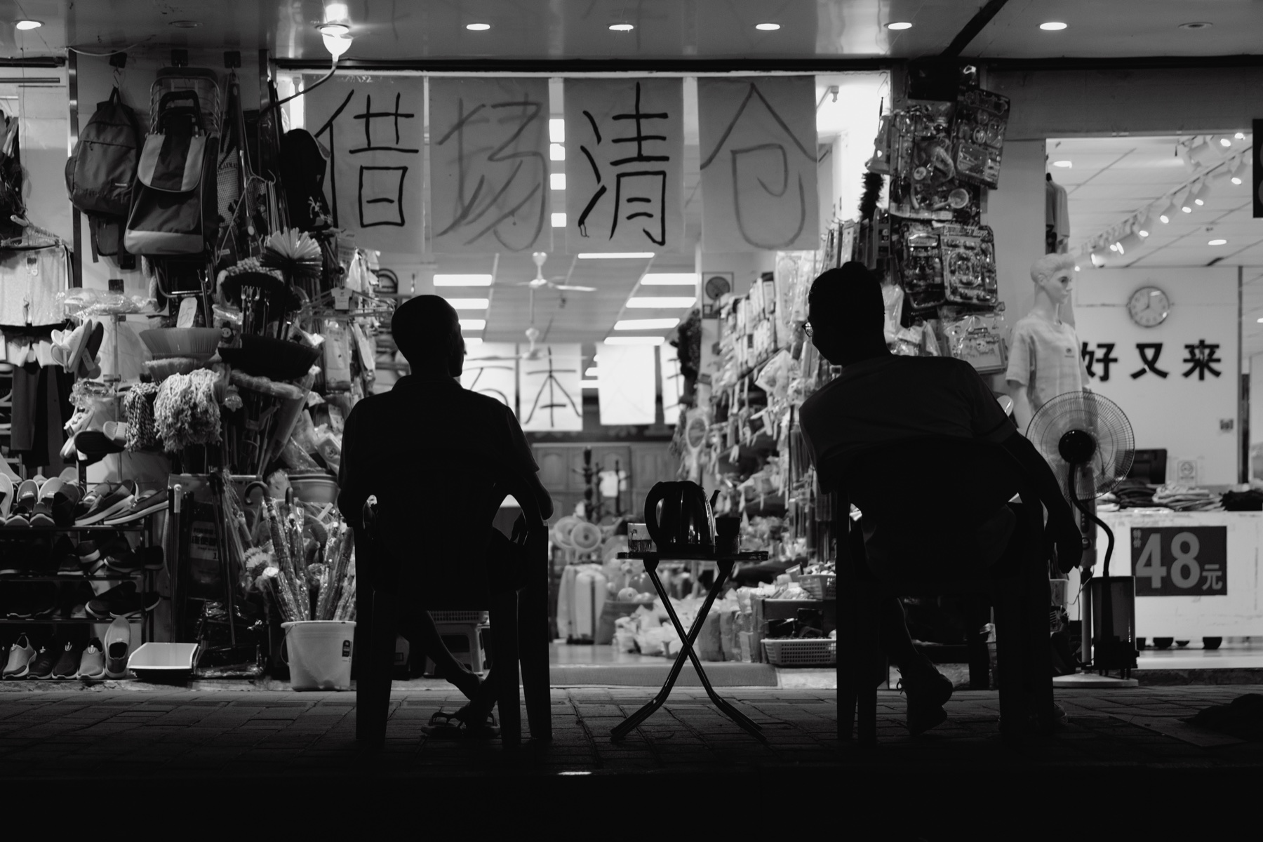 商店门前相对而坐的两个人