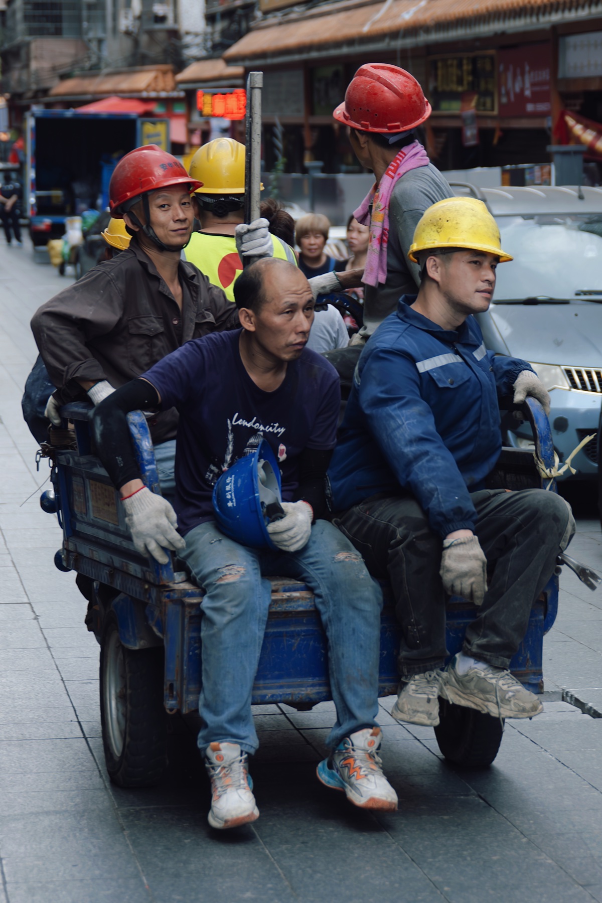 乘坐三轮车经过街道的建筑工人